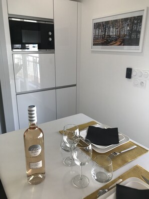 A modern kitchen with white cabinets, a stainless steel oven, and a dining area with a table set for four. - Appt NEW Arcachon Center, Beach 250 m - Terrace - Private car park (Arcachon)