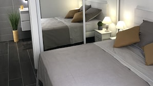 A modern bedroom with a large bed, bedside tables, a mirror, and a hanging light fixture. - Appt NEW Arcachon Center, Beach 250 m - Terrace - Private car park (Arcachon)