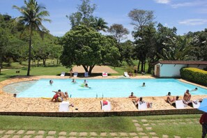 Una piscina al aire libre, sombrillas, sillones reclinables de piscina