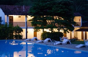 Una piscina al aire libre, sombrillas, sillones reclinables de piscina