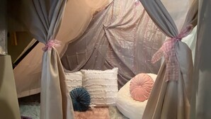 A cozy tent-like room with a soft, plush floor, a bed with pillows, and curtains tied at the top. - Prairie Cottages in historic Rapid City (Rapid City)