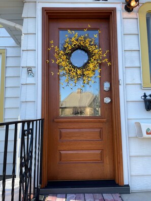 Une porte d’entrée en bois avec un panneau de verre, une couronne décorative et une boîte aux lettres.