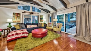 A spacious living room with a large window, a red ottoman, and a cozy fireplace. - New! Majestic Mountain Retreat (Incline Village)
