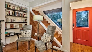 A modern interior with a staircase, bookshelves, two patterned armchairs, and a red door. - New! Majestic Mountain Retreat (Incline Village)