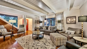 A spacious living room with a high ceiling, wooden floors, and a large window offering a view of the outdoors. - New! Majestic Mountain Retreat (Incline Village)