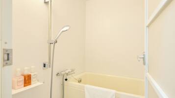 A bathroom with a bathtub, a showerhead, and a shelf with toiletries.