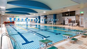 Una piscina interior con carriles delimitados, una torre de socorrista y zonas de estar.
