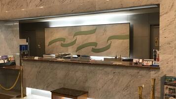 A reception desk with a marble counter, a bench, and a wall-mounted screen displaying abstract art.