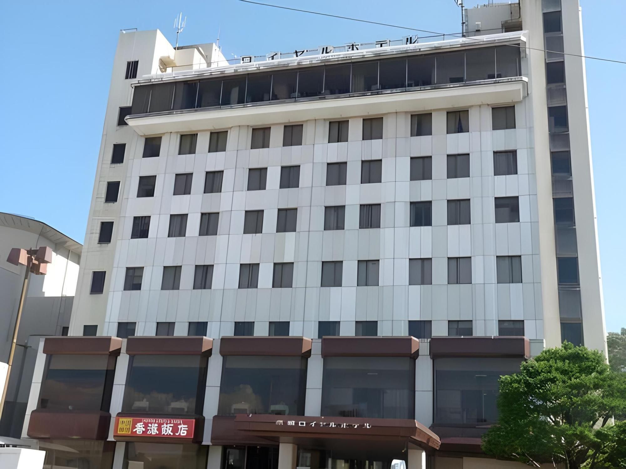 A multi-story building with a flat facade, large windows, and a ground-level entrance with signage.