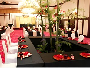 Une salle à manger élégante, avec des chaises et des tables blanches, un arrangement floral central et un lustre.