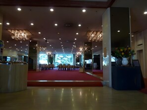 A spacious lobby with a red carpet, multiple seating areas, and a large digital display. - Royal Hotel Miyakonojo (Miyakonojo)