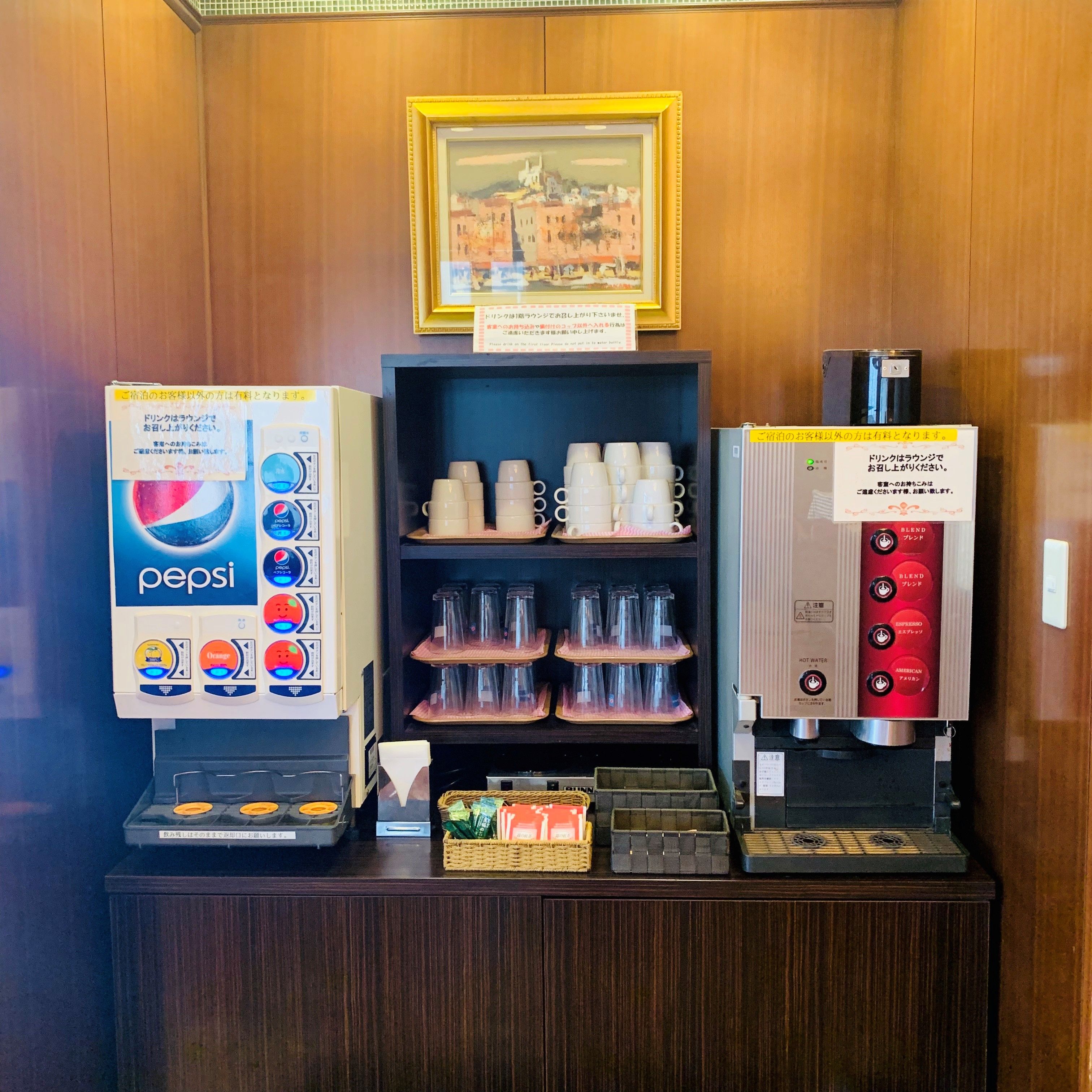 A vending machine area with a Pepsi dispenser, a coffee machine, and a shelf with cups.