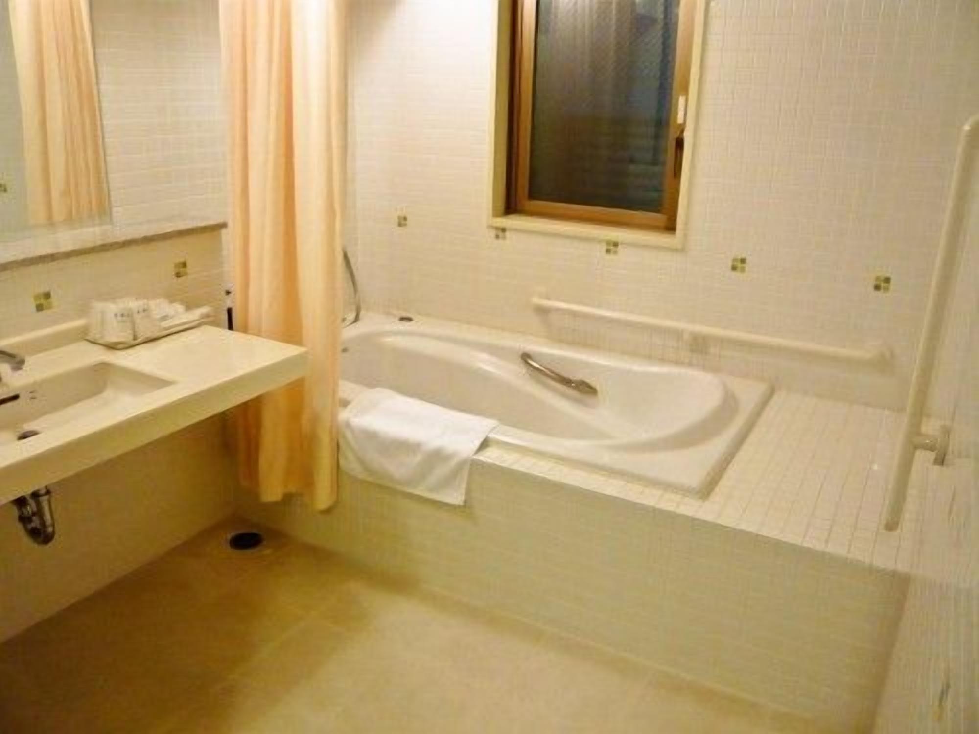A bathroom with a bathtub, a sink, and a window.