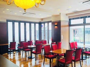 A restaurant with red chairs and tables, large windows, and a yellow chandelier. - Regalo Hotel Okayama (Okayama)