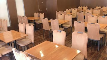 Un salón de conferencias con varias mesas y sillas, una puerta que indica 'STAFF ONLY' y suelo de madera.