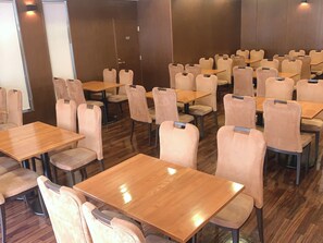 Un salón de conferencias con varias mesas y sillas, una puerta que indica 'STAFF ONLY' y suelo de madera.