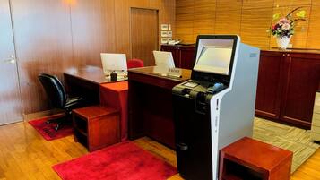 Una recepción de hotel con una computadora, un teléfono y una planta pequeña.