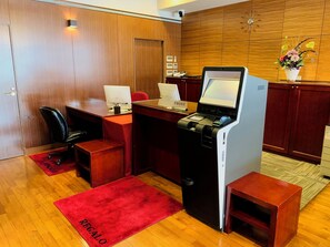 A hotel reception desk with a computer, a telephone, and a small plant. - Regalo Hotel Okayama (Okayama)