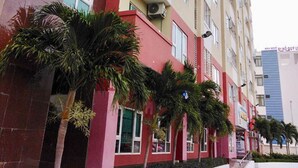 A multi-story residential building with balconies, air conditioning units, and a red and beige facade. - WELCOME TO MOONLIGHT OSC (Tp. Vũng Tàu)