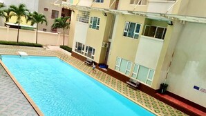 A swimming pool adjacent to a building with multiple windows and a tiled walkway. - WELCOME TO MOONLIGHT OSC (Tp. Vũng Tàu)
