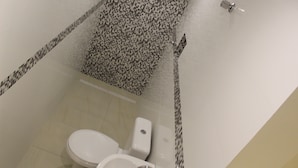 A bathroom with a toilet, bidet, and a shower area with a tiled floor and walls. - Gran Palazzo Hotel (São Paulo)