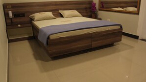 A modern hotel room with a wooden bed, a nightstand, a mirror, and a potted plant. - Gran Palazzo Hotel (São Paulo)