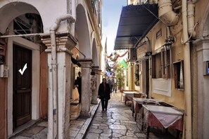 A narrow street with stone pavement, historic buildings, and a person walking.