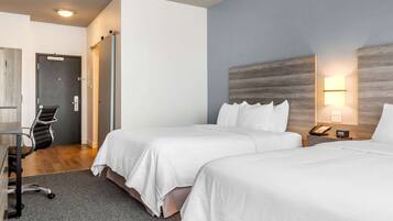 Una habitación de hotel con dos camas, un escritorio, una silla y una puerta.