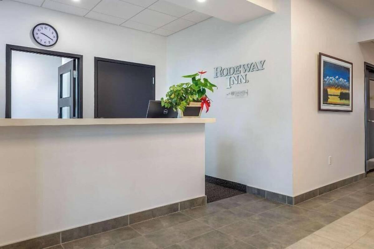 A reception desk with a clock, a potted plant, and a sign for Rodeway Inn.
