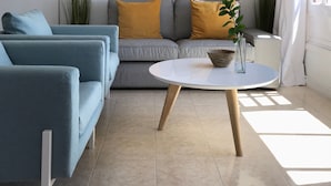 A modern living room with a grey sofa, blue armchair, and a round coffee table.