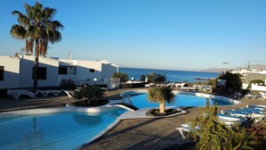 A resort with a swimming pool, lounge chairs, and a view of the sea.