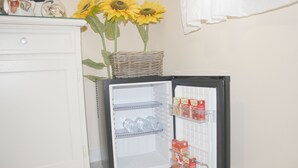 Un refrigerador pequeño con repisas transparentes, una cesta de mimbre encima y algunos objetos en su interior.