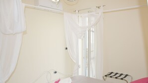 Una habitación de hospital con cama, ventana con cortinas, un calentador en la pared y una mesita de noche.
