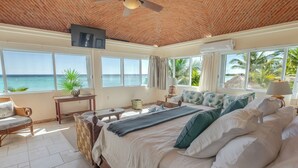 Un dormitorio con una cama grande, televisor y vistas al océano.
