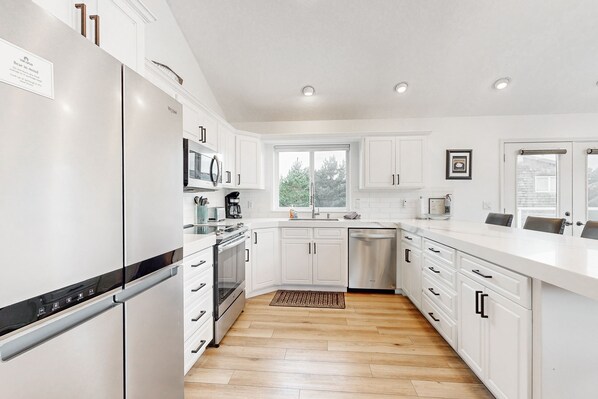 Enjoy cooking in this well-equipped kitchen with a window and wooden floor.
