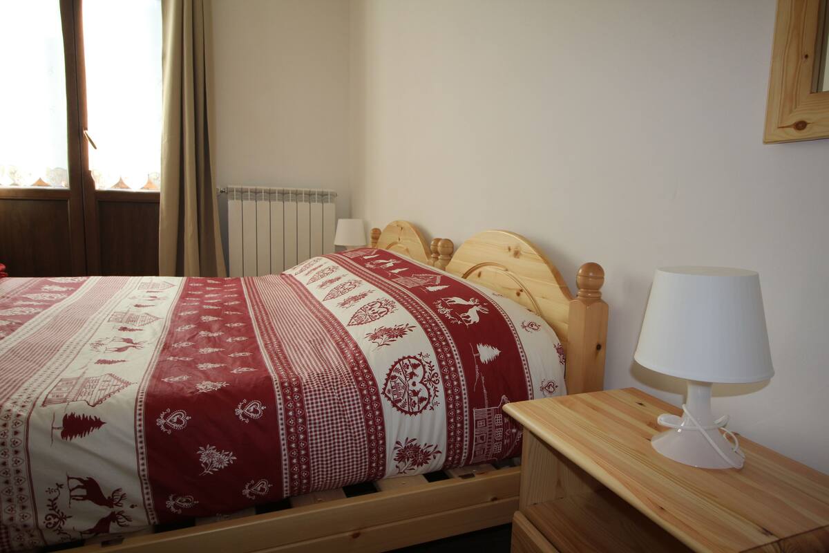 A neatly made bed with a patterned bedspread, a wooden headboard, and a bedside table with a lamp.