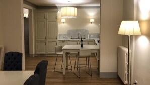 A modern kitchen with white cabinets, a central island, and pendant lighting. - Luxury in the Piazza in Greve In Chiant (Greve in Chianti)