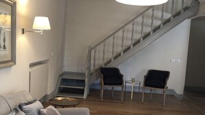 A living room with a staircase, a sofa, two armchairs, and a small round table. - Luxury in the Piazza in Greve In Chiant (Greve in Chianti)