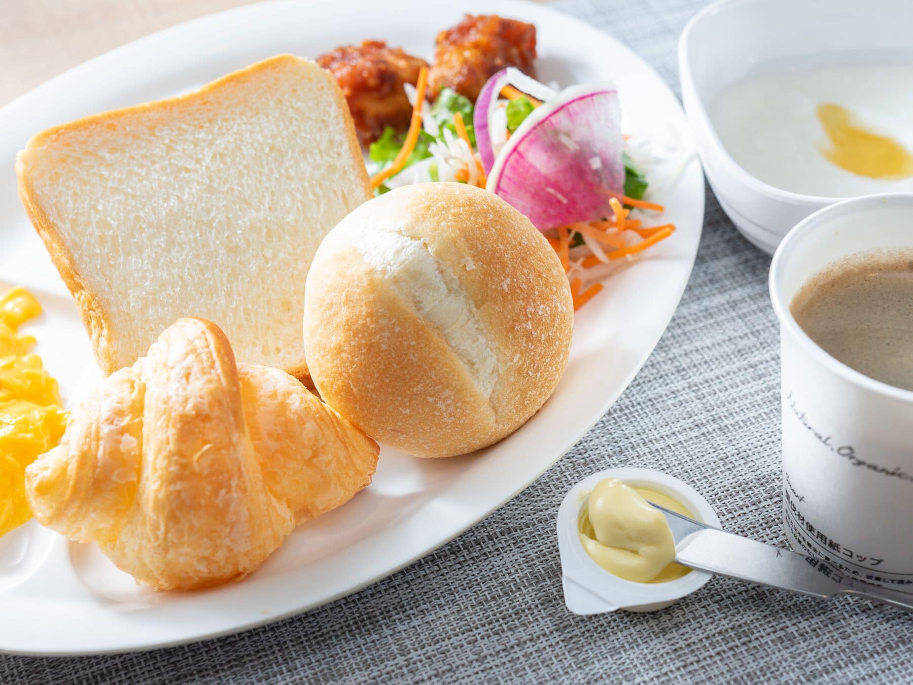 Ein Teller mit Brot, Croissants, Salat und Suppe.