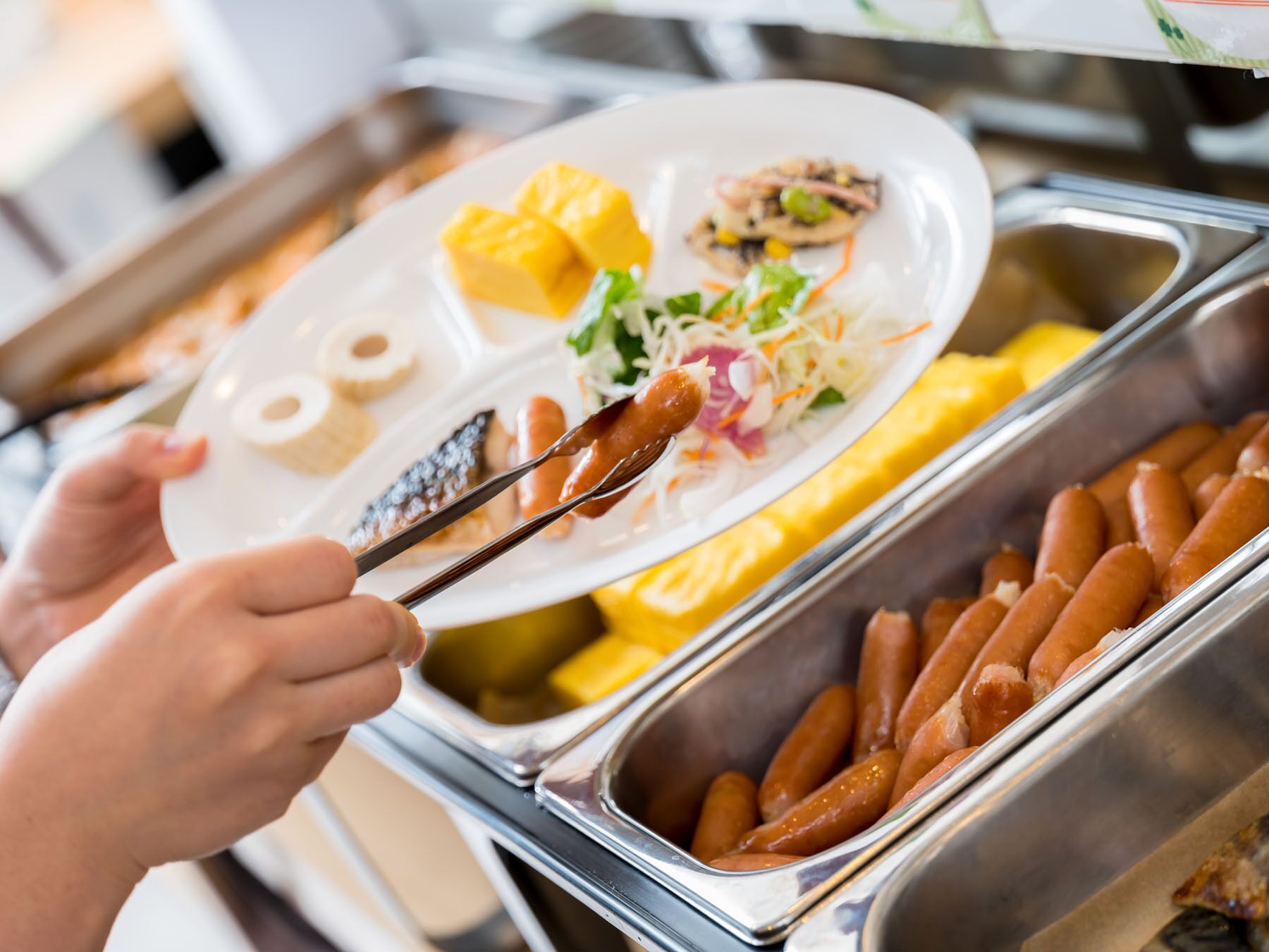 A buffet with various food items including sausages, a salad, and fruit.