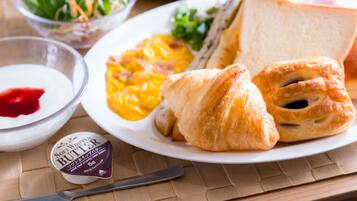 A breakfast plate with croissants, scrambled eggs, and a side salad.