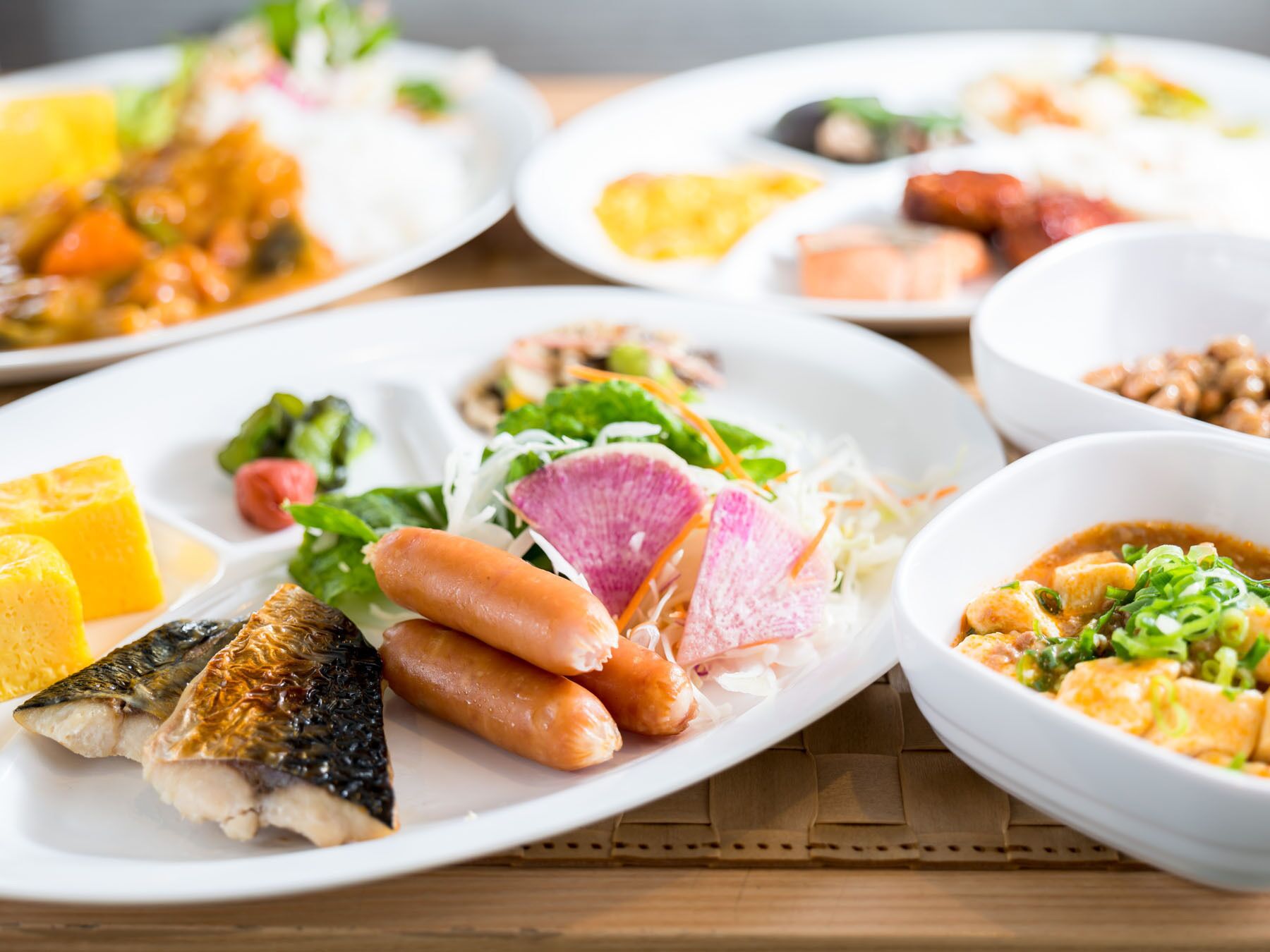 Variedad de platos en blanco, con pescado, salchichas y verduras.