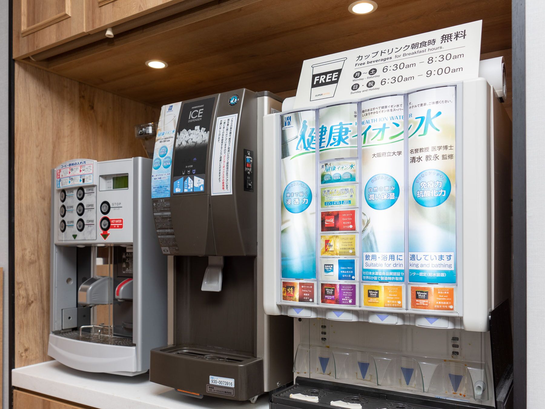 A coffee machine and a water dispenser with various drink options and a sign indicating free beverages for breakfast hours.