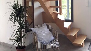 Un intérieur moderne avec un escalier en colimaçon, une plante en pot et une chaise à rayures.