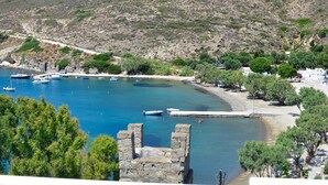Zona costera con barcos amarrados, una playa y un muro de piedra.