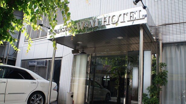 Ingresso di un hotel con porta in vetro, tappeto blu e insegna sopra la porta.