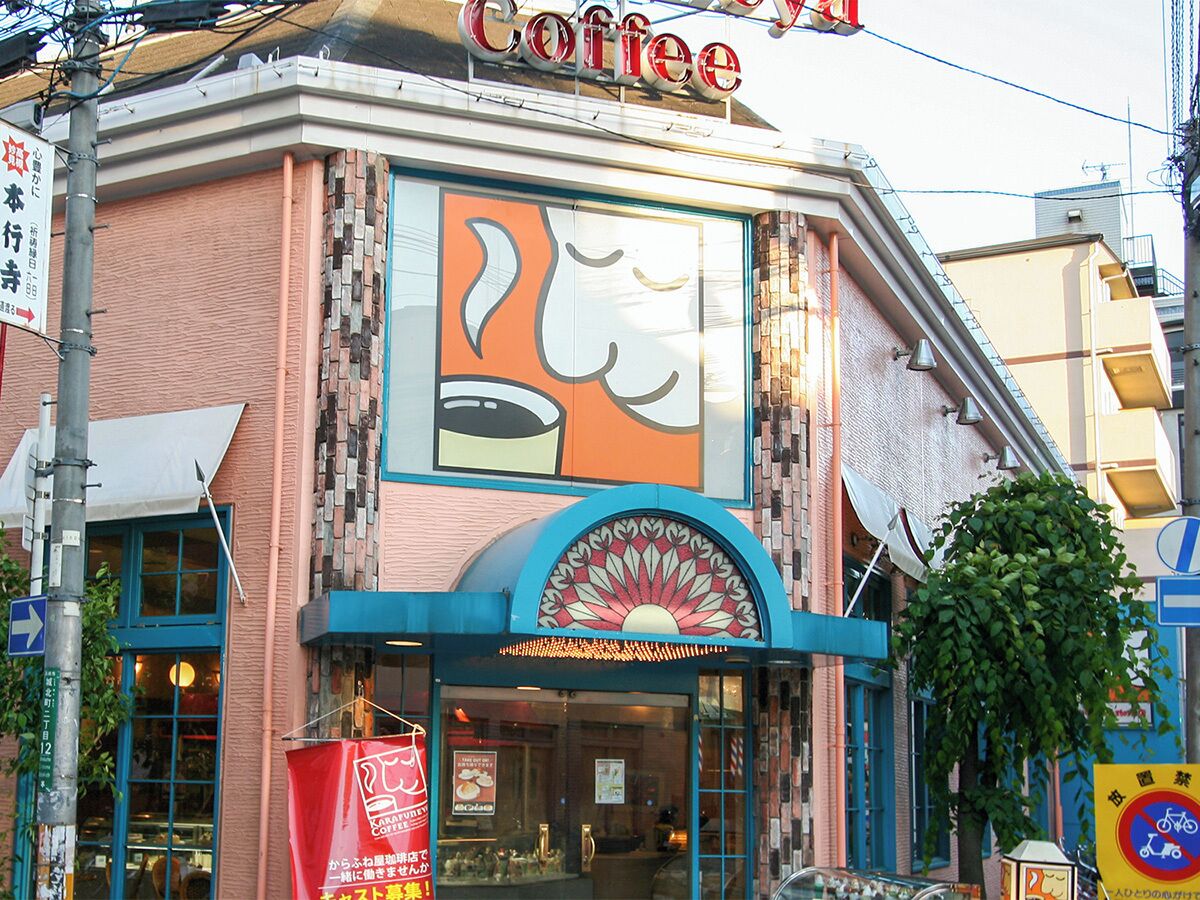 A building with a large coffee shop sign and a colorful mural.