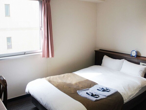 Une chambre d’hôtel avec un lit, une table de chevet, une fenêtre avec des rideaux et une horloge murale.