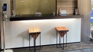 Una reception con una sveglia digitale, uno specchio e due sgabelli di legno.