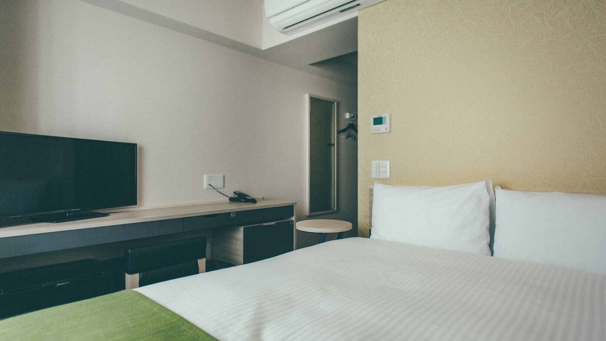 Ein Hotelzimmer mit Bett, Fernseher, Schreibtisch und Spiegel.